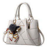 White handbag with decorative keychain on a white background
