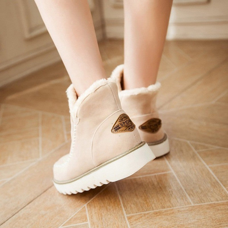 Beige winter boots with heart details on a wooden floor