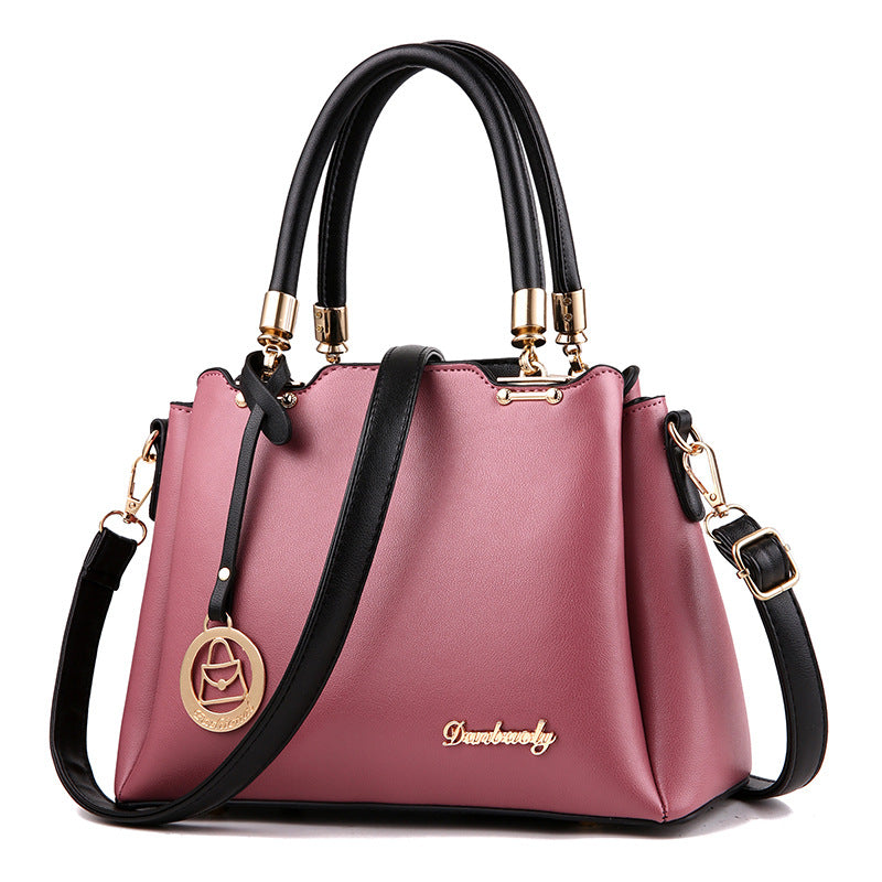 Pink handbag with black handles and strap on a white background