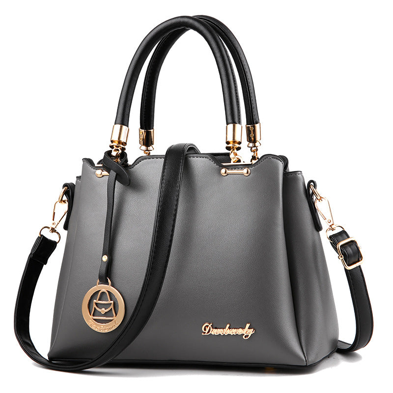 Gray handbag with black handles and strap on a white background