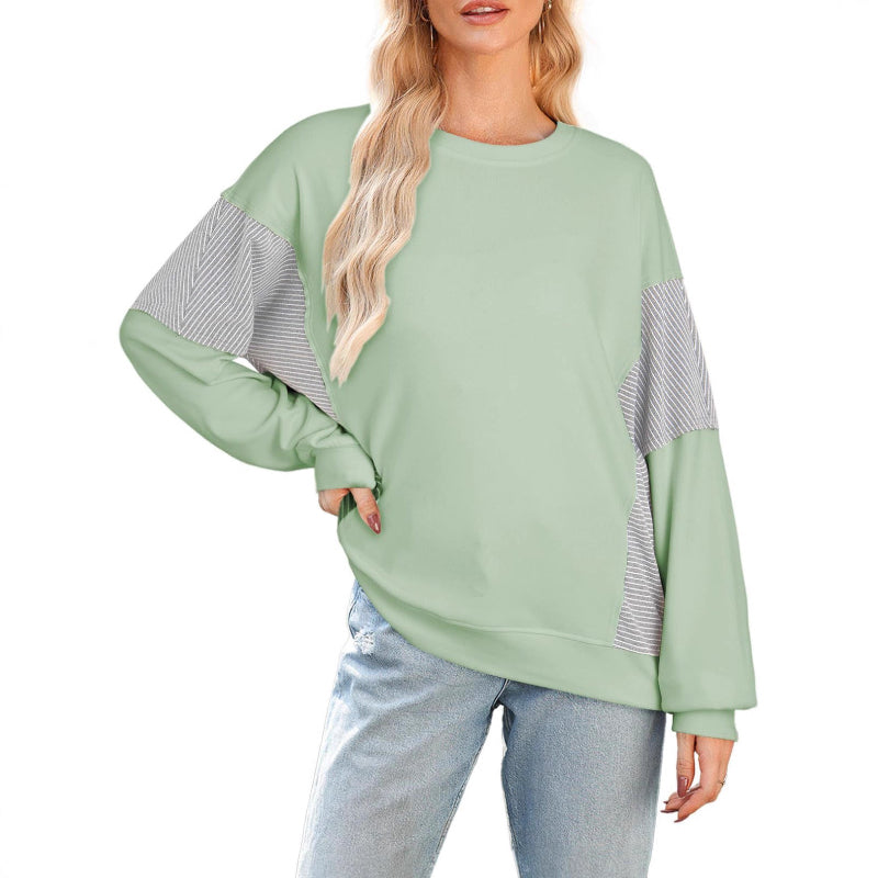 Light green sweater with gray striped sleeves worn by a person on a white background