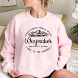 Person wearing a pink sweatshirt with motivational text and mountain graphic