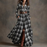 Woman wearing a long plaid dress with a belt and brown boots against a gray background