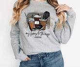 Gray sweatshirt with a graphic design and text worn by a person on a white background