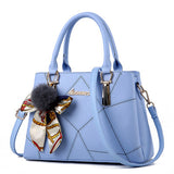 Blue handbag with a decorative scarf and pom-pom on a white background