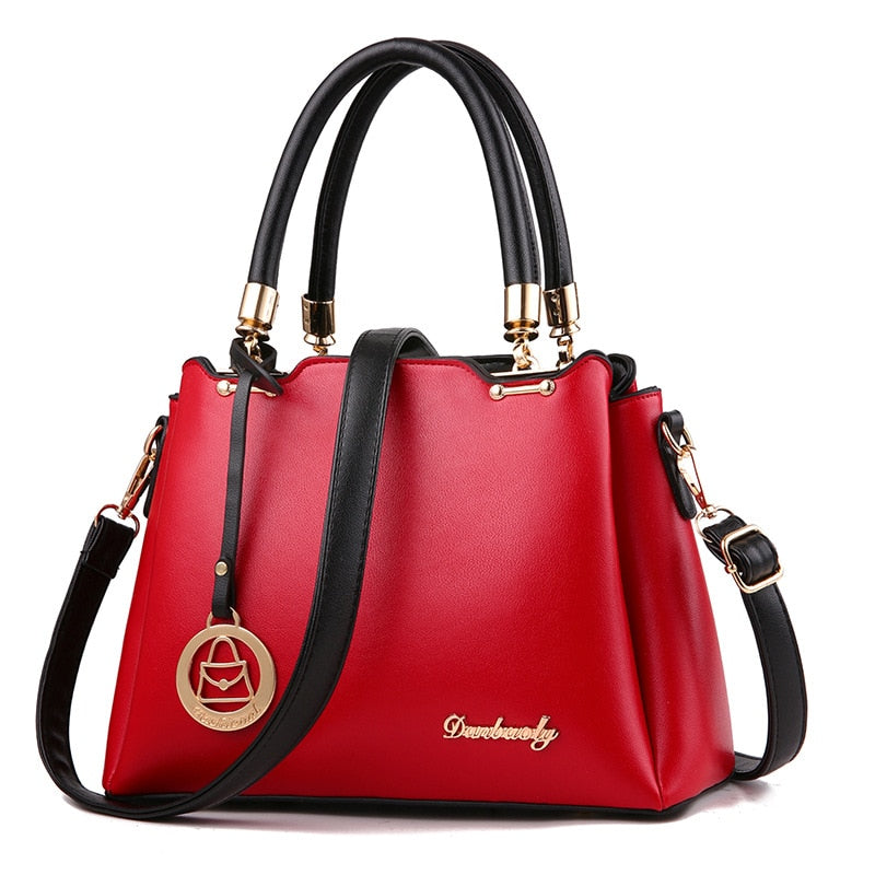 Red handbag with black handles and strap on a white background