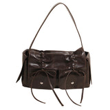 Brown leather handbag with decorative bows on a white background