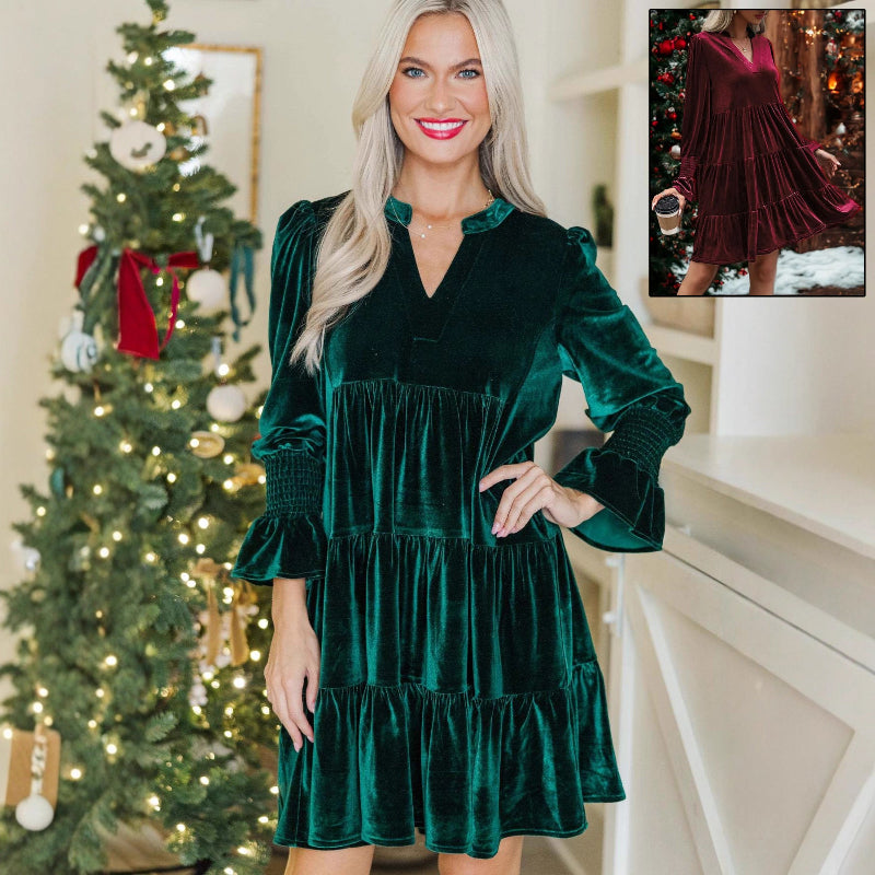 Woman wearing a green velvet dress in front of a decorated Christmas tree.