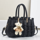Black handbag with a teddy bear keychain on a white background