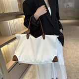 Person holding a white tote bag with brown handles in an indoor setting