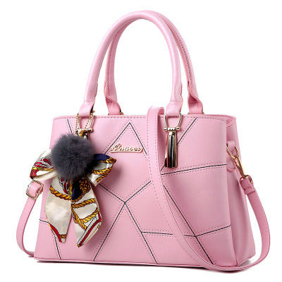 Pink handbag with a decorative ribbon and fluffy pom-pom on a white background