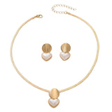 Gold necklace and earrings with heart-shaped designs on a white background