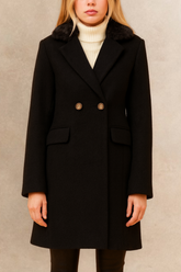Person wearing a black coat with fur collar against a neutral background