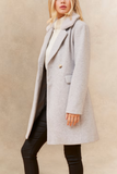 Person wearing a gray coat against a beige background