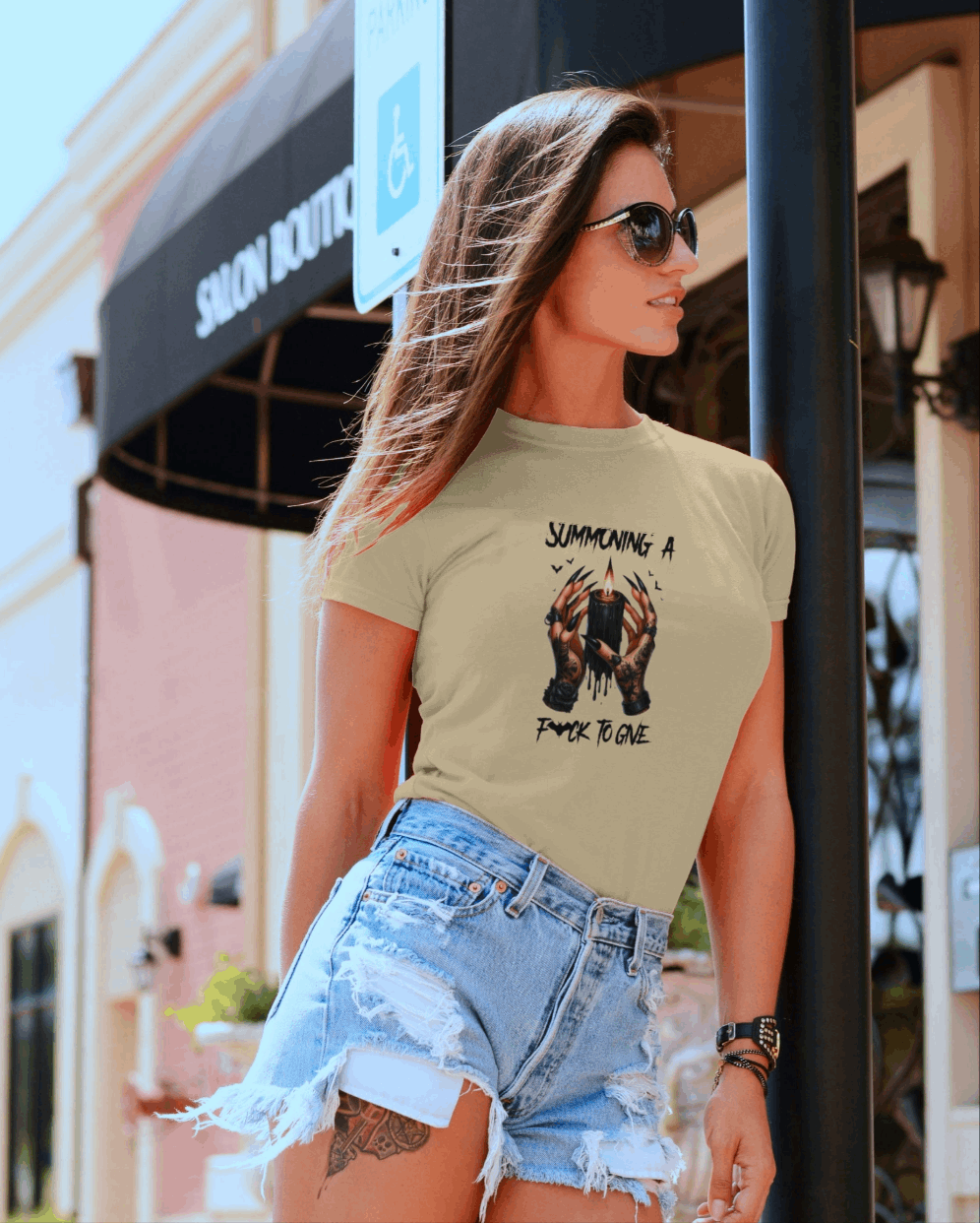 Woman wearing a graphic t-shirt and denim shorts standing outdoors.