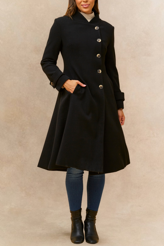 Person wearing a black coat with silver buttons on a beige background