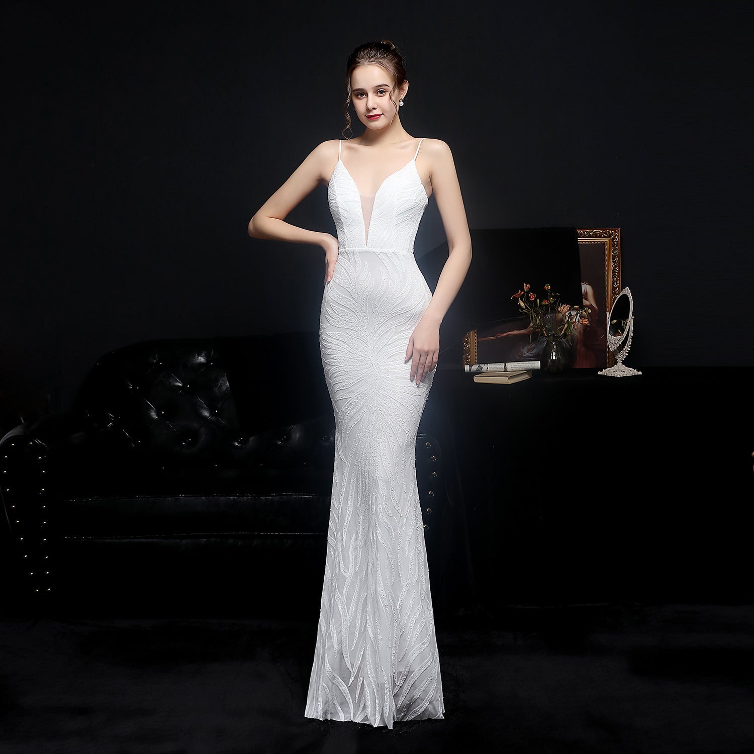 Woman in a white evening gown standing against a dark background