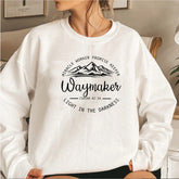 Person wearing a white sweatshirt with motivational text and mountain design.