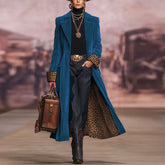 Model wearing a blue coat with leopard print accents, holding a suitcase on a runway.