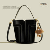 Black leather handbag with a decorative keychain on a beige background