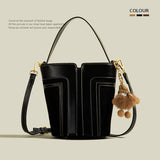 Black leather handbag with a decorative keychain on a beige background