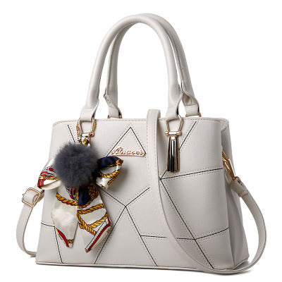 White handbag with decorative keychain on a white background