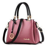 Pink handbag with black handles and strap on a white background