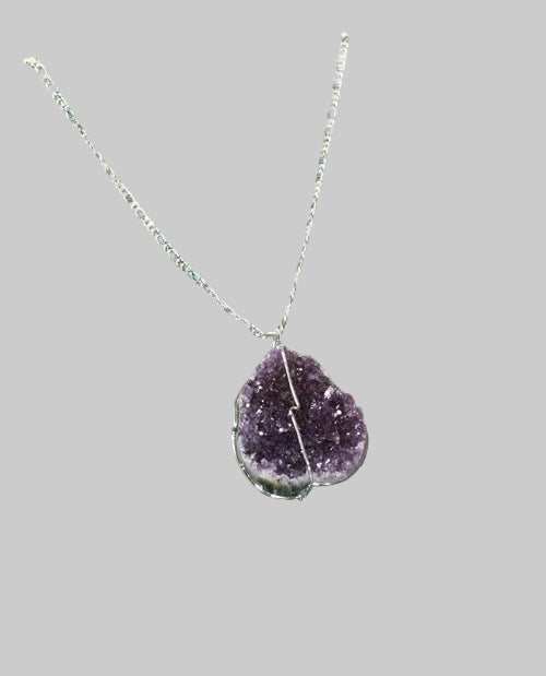 Necklace with a purple teardrop-shaped pendant on a glass surface