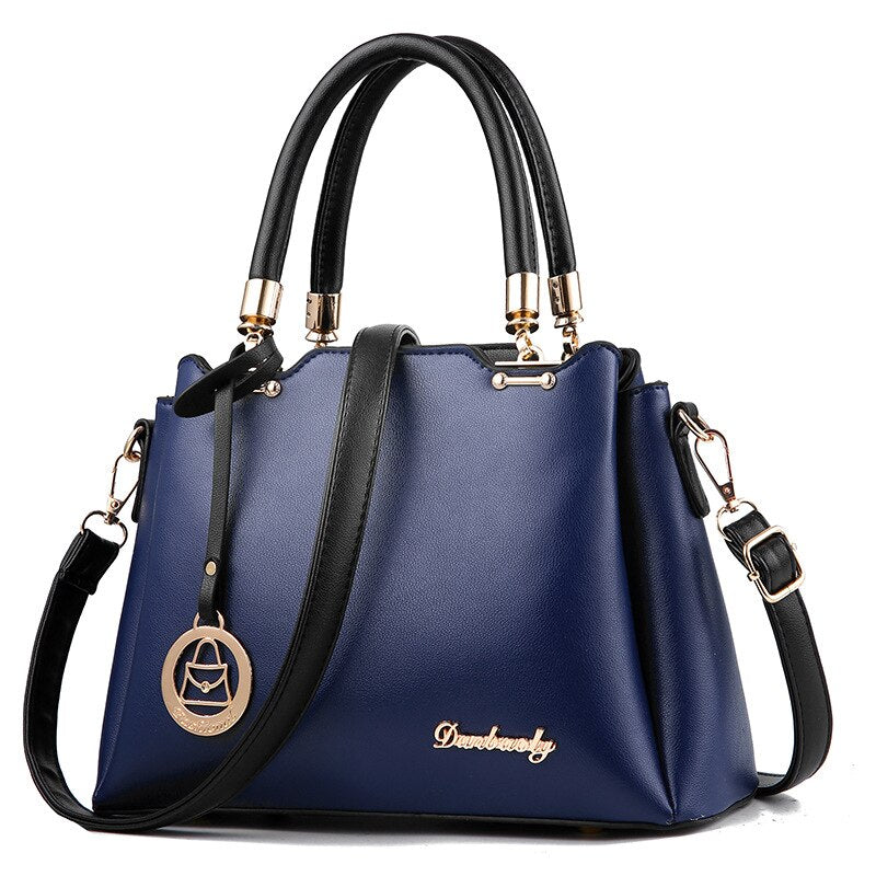 Blue handbag with black handles and strap on a white background
