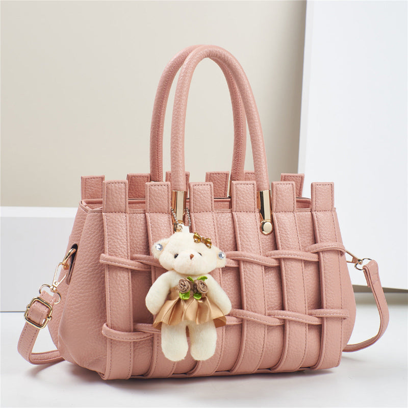 Pink woven handbag with a teddy bear keychain on a light background