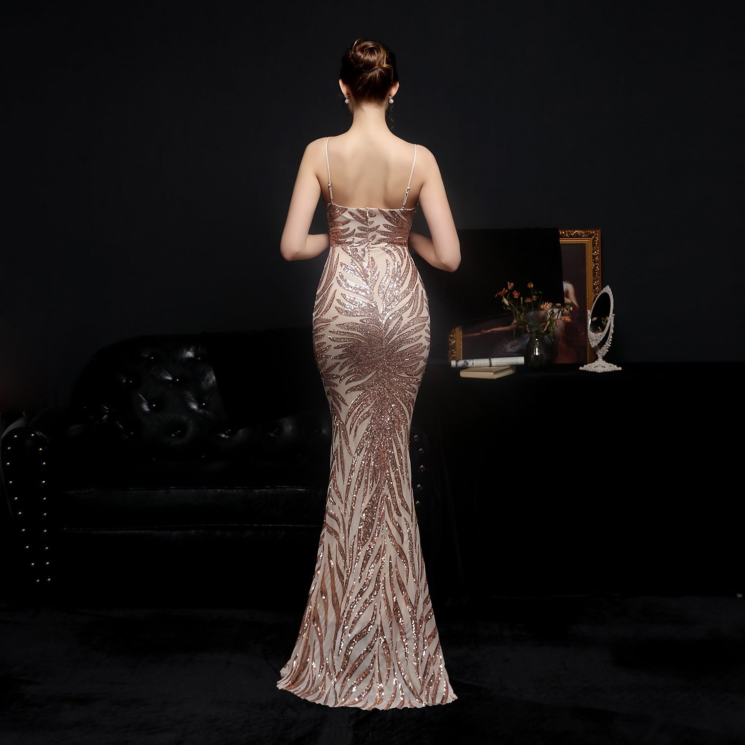 Woman in a sparkly evening gown standing in a dimly lit room.