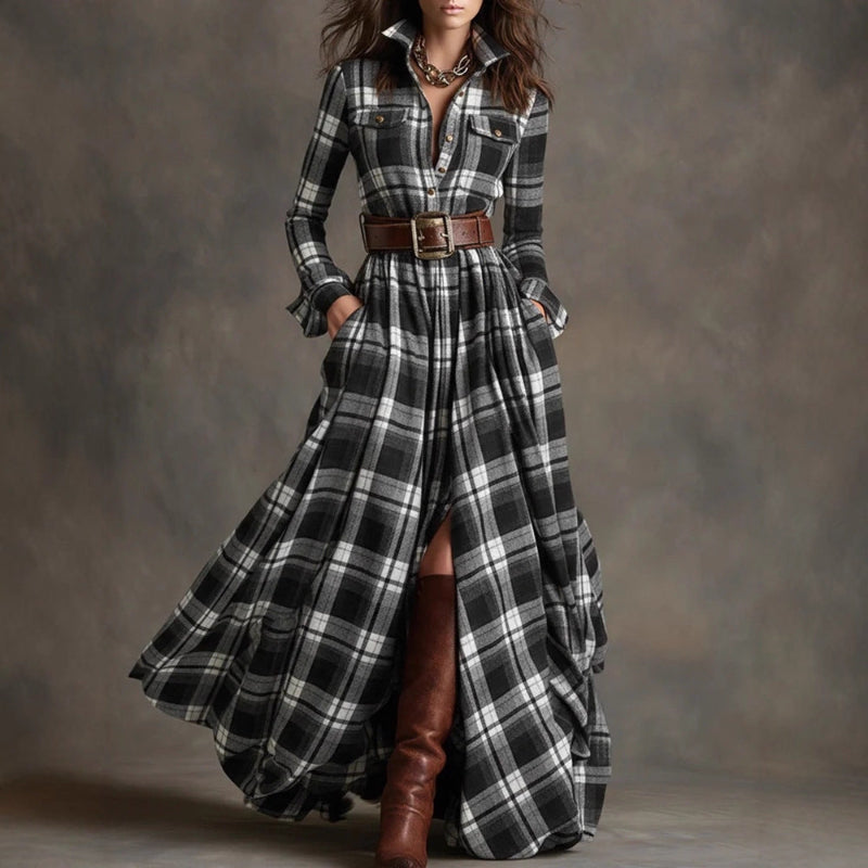Woman wearing a long plaid dress with a belt and brown boots against a gray background