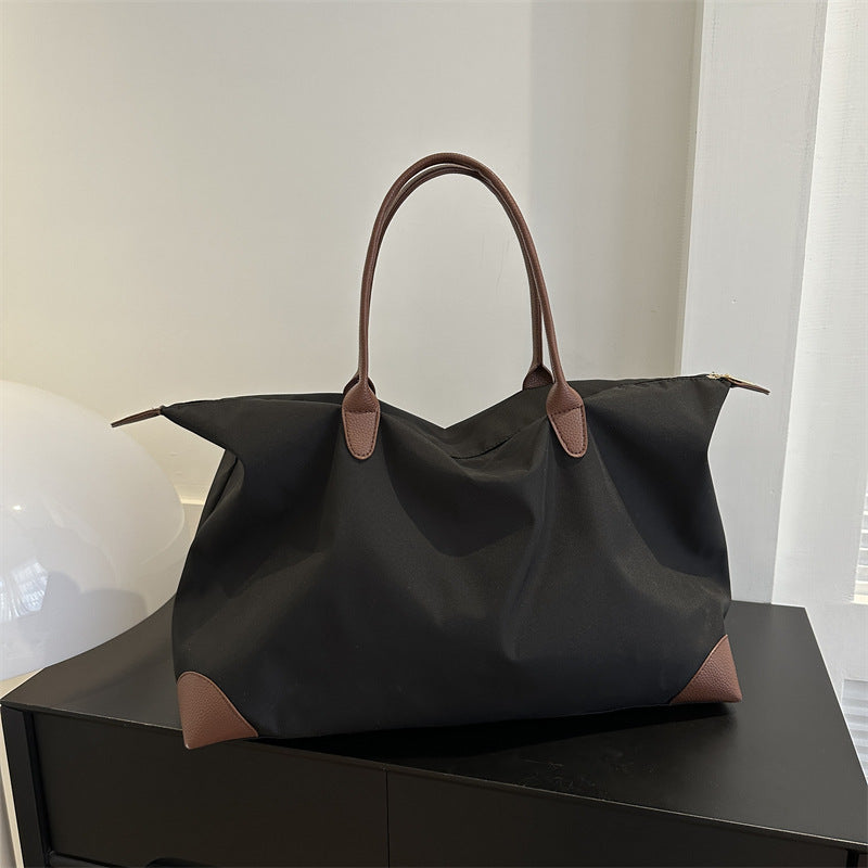 Black handbag with brown handles and accents on a black surface.