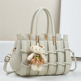 Light gray woven handbag with a teddy bear charm on a light background