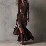 Woman wearing a brown dress with a belt and matching boots, holding a brown handbag against a gray background.