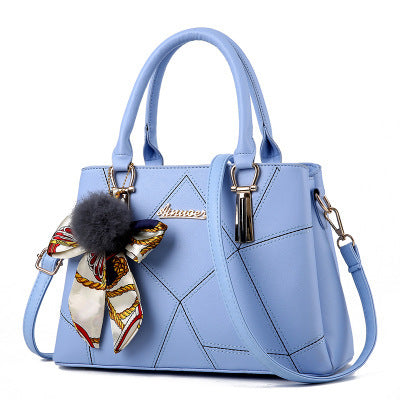 Blue handbag with a decorative scarf and pom-pom on a white background
