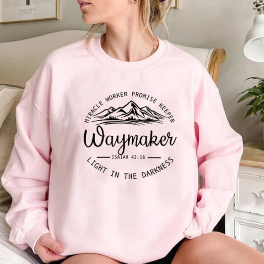 Person wearing a pink sweatshirt with motivational text and mountain graphic