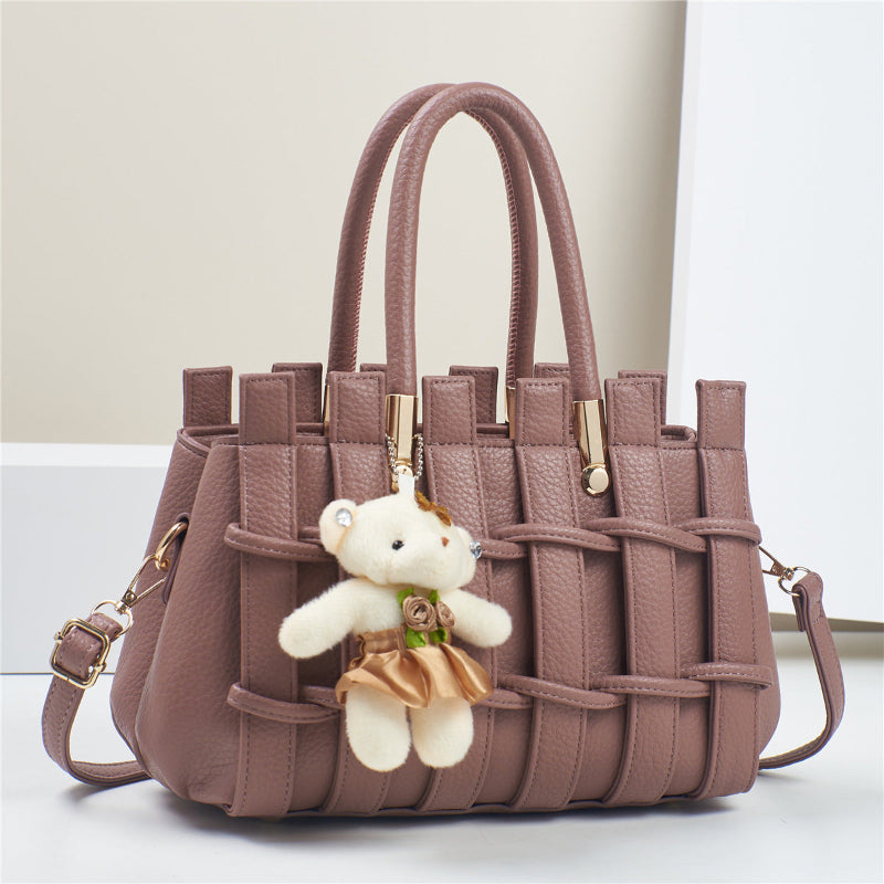 Pink woven handbag with a teddy bear charm on a light background