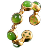 Gold earring with green gemstones on a white background