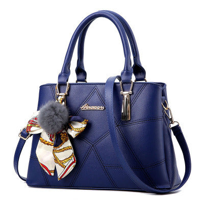 Blue handbag with a decorative bow and fur pom-pom on a white background