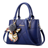 Blue handbag with a decorative bow and fur pom-pom on a white background