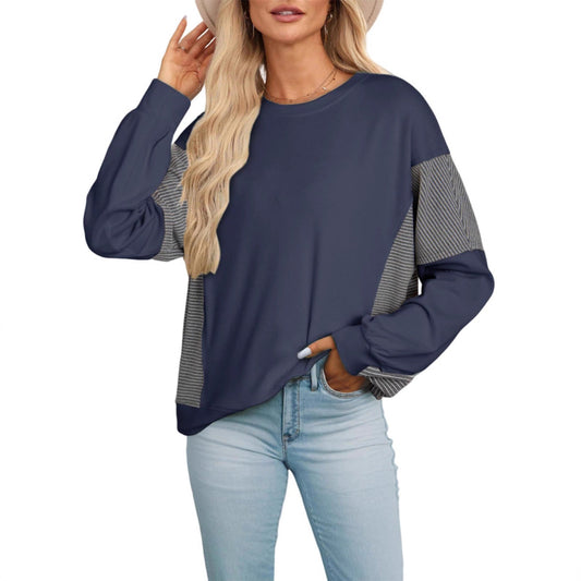 Woman wearing a navy blue sweater with patterned sleeves on a white background