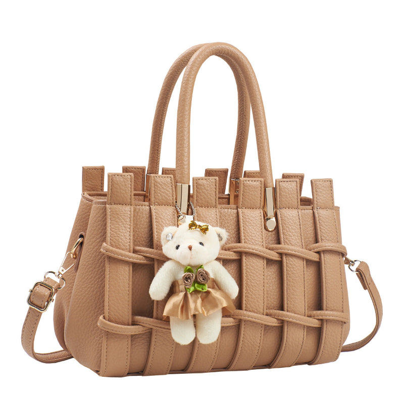 Beige handbag with a teddy bear charm on a white background