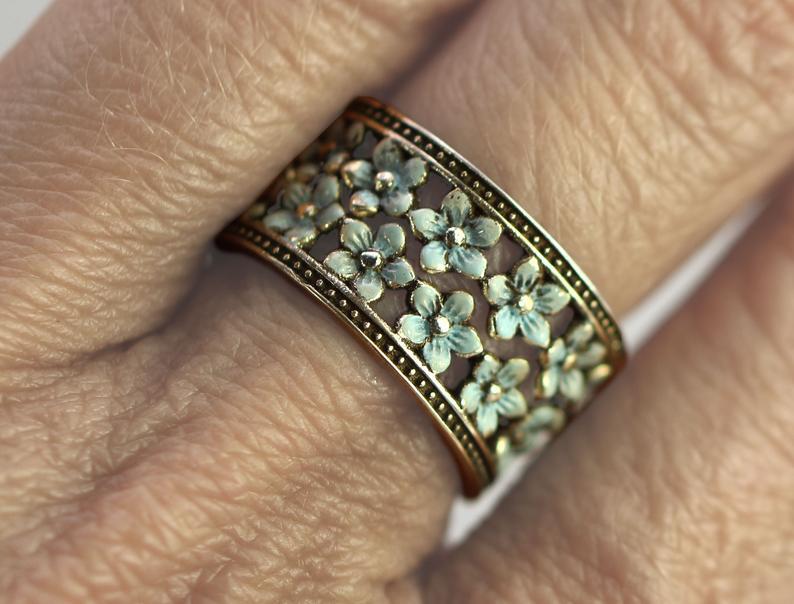 Gold ring with floral design on a finger