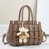 Brown woven handbag with a teddy bear keychain on a white background