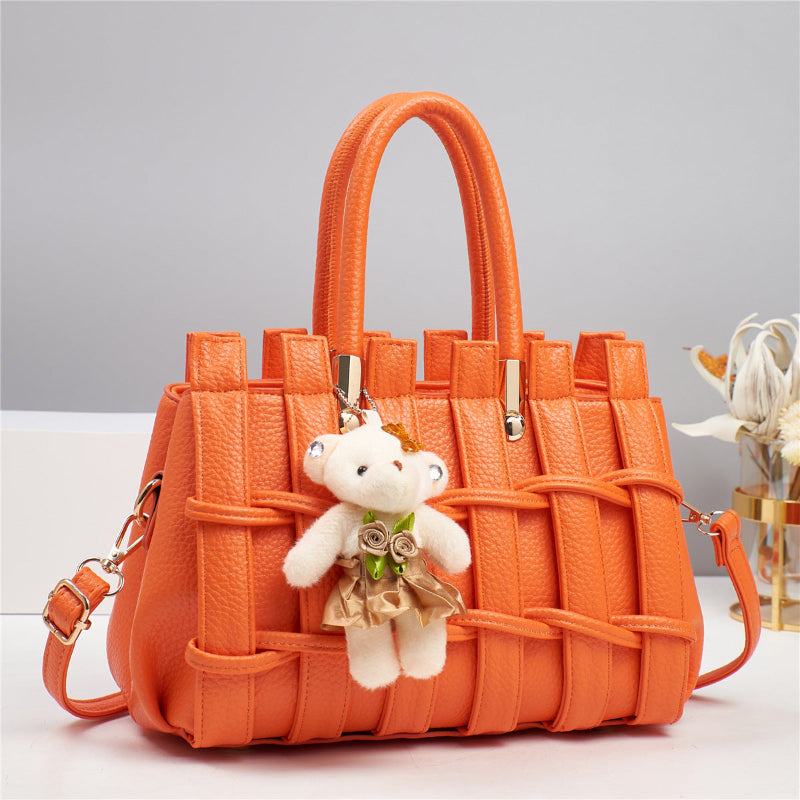 Orange woven handbag with a teddy bear keychain on a light gray background