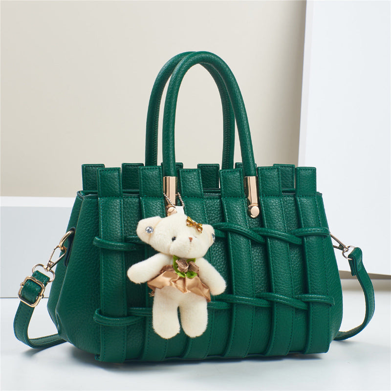 Green handbag with a teddy bear charm on a light background