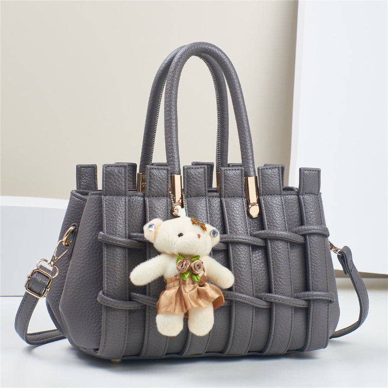 Gray woven handbag with a teddy bear keychain on a light background