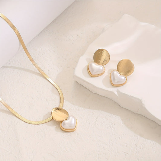 Gold necklace and heart-shaped earrings on a white surface