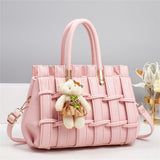 Pink textured handbag with a teddy bear charm on a light gray background